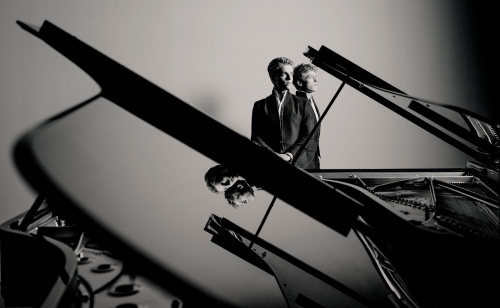 Na tle czarnego fortepianu widać dwóch pianistów