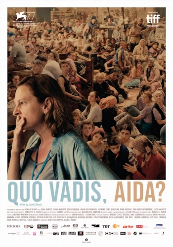 Kadr z filmu dużo stłoczonych ludzi siedzących na ziemi oraz na pierwszym planie kobieta zamyślona z ręka na ustach