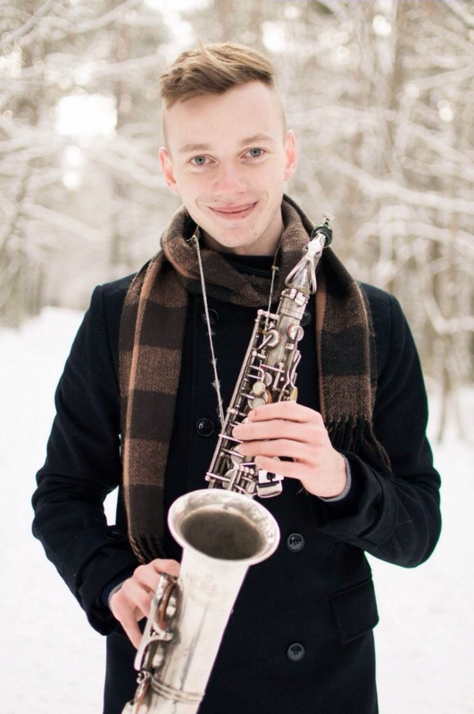 Muzyk z saksofonem i szalikiem na szyi, zdjęcie w plenerze sceneria zimowa