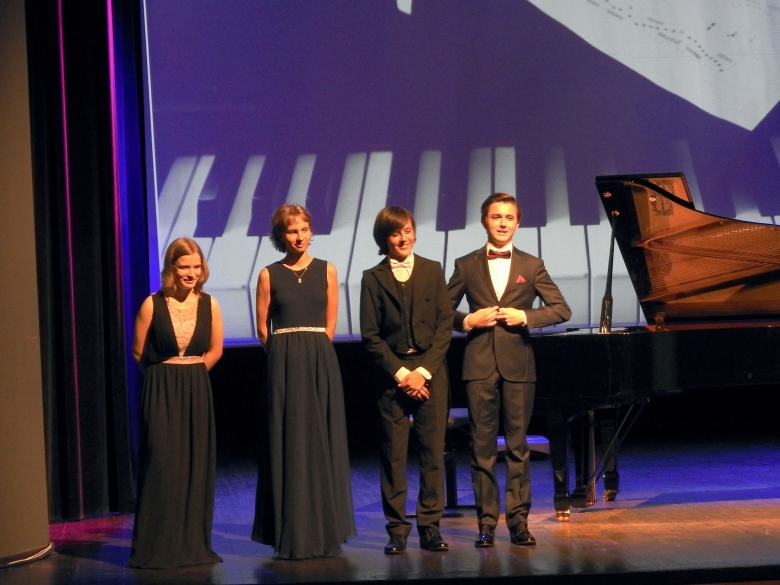 Czworo uczestników festiwalu stoi na scenie, w tle widać fortepian i logo festiwalu