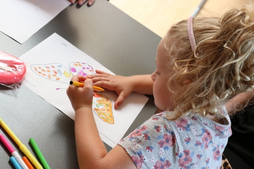 Młoda dziewczynka maluje kolorowymi kredkami na papierze w ramach zajęć