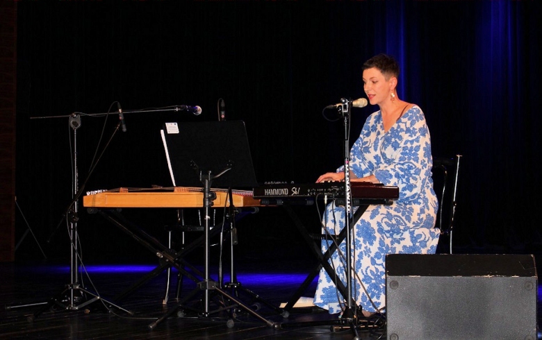 Autorka Ania Brody siedzi przed instrumentem klawiszowym na scenie
