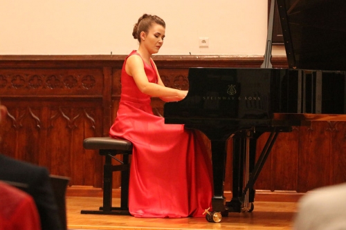 Pianistka w czerwonej sukni gra na czarnym fortepianie podczas koncerty