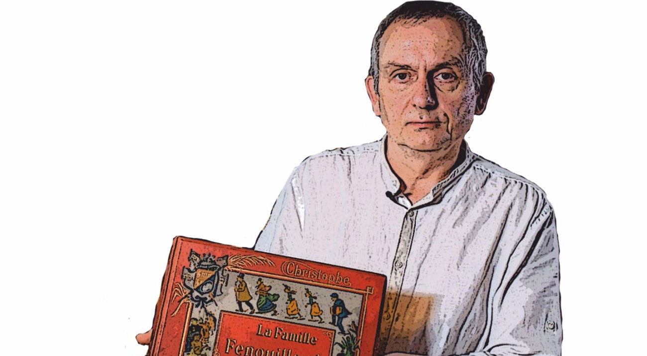 Wojciech Jaka trzyma w ręku czerwony komiks w twardej okładce