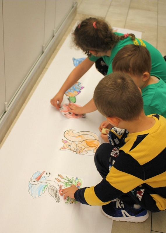 Dzieci pracują rysując na dużych kartonach różne zwierzęta w tym wiewiórka, bocian