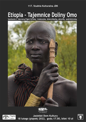 Na plakacie zdjęcie czarnoskórej Etiopki, która ma ogoloną głowę w ręce trzyma kij