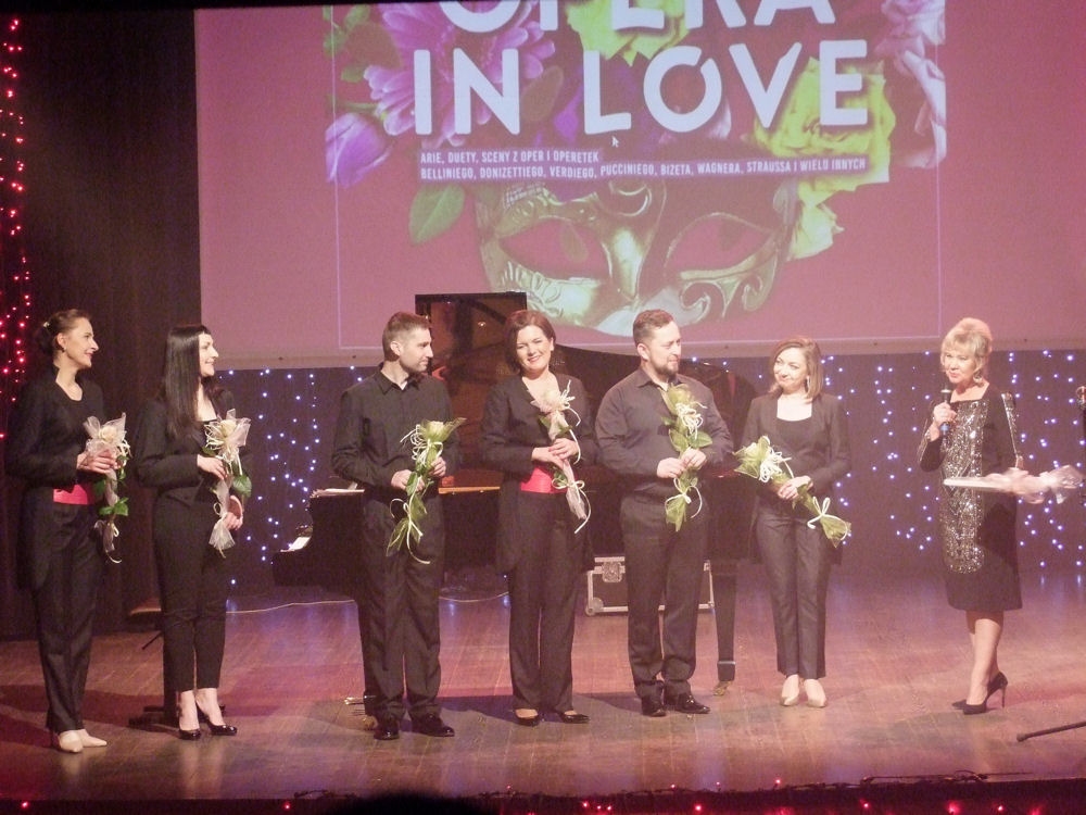 Scena finałowa muzycy stoją na scenie z kwiatami w ręku.