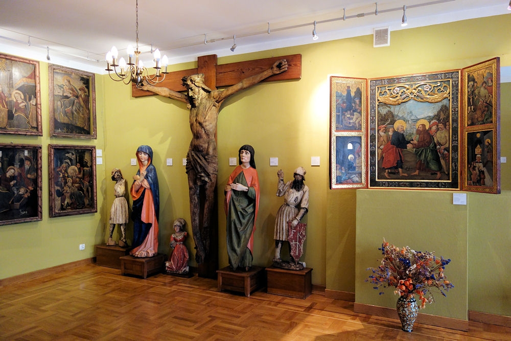 W centrum sali widać duży krzyż z Chrystusem, obok figurki świętych , na ścianach wiszą obrazy i ikony
