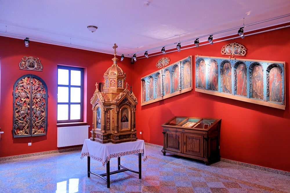 Czerwone ściany sali na środku ikonostas. Na ścianach ikony.