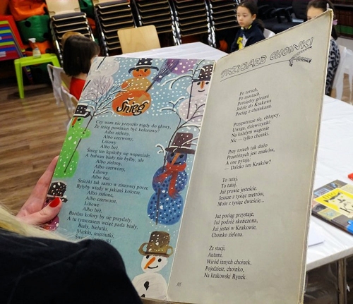 W centrum widać książkę dla dzieci. Z prawej strony widać tekst wiersz z lewej rysunek bałwanka.