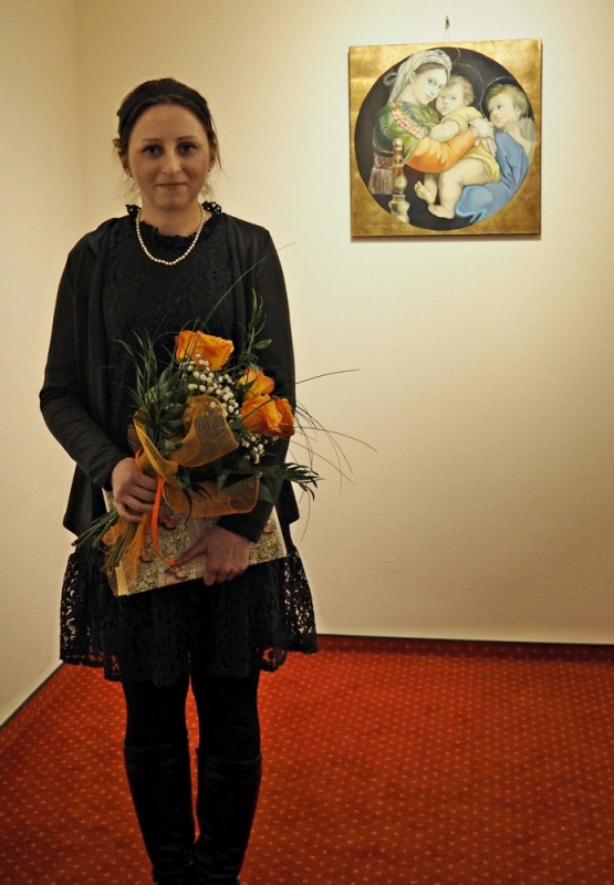 Anna Gołojuch trzyma w ręku bukiet kolorowych kwiatów i książkę.