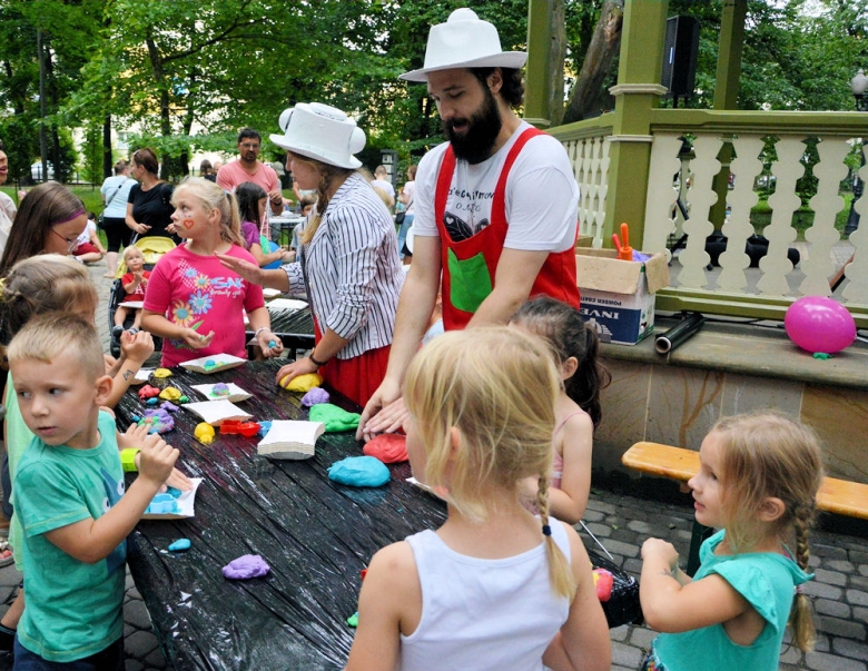 Dzieci uczestniczą w warsztatach lepienia plasteliną w plenerze w parku