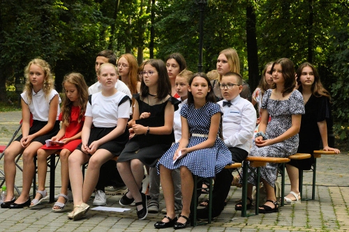 Te same dzieci tym razem siedzą na ławkach w miejscu publiczności