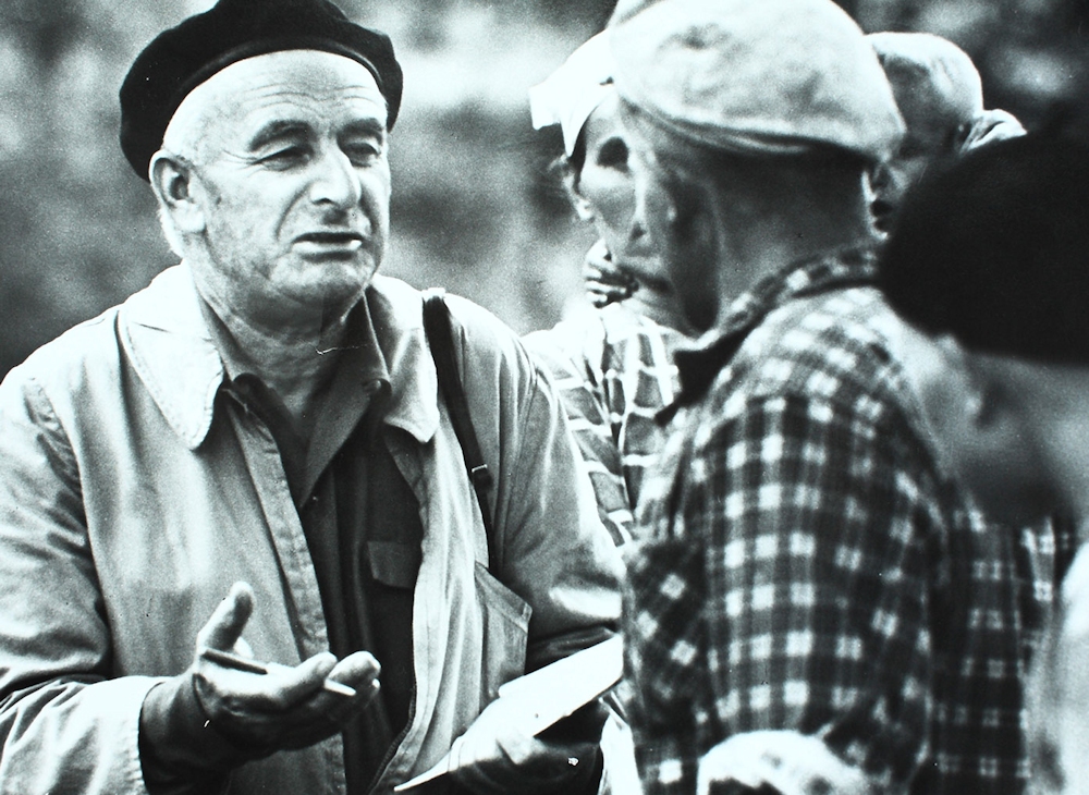 Czarno-białe stare zdjęcie. Franciszek Kotula z kimś rozmawia na głowie ma czarny beret i gestykuluje lewą ręką