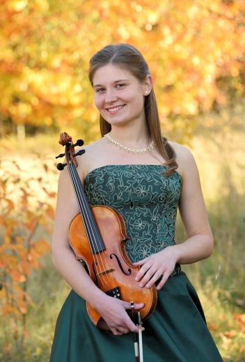 Zdjęcie skrzypaczki z instrumentem w tle widać jesienną scenerię